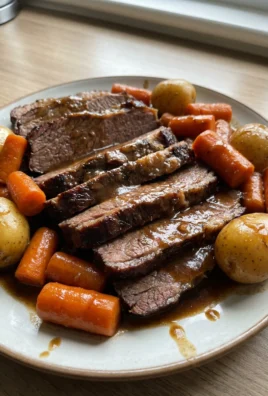 A white platter holding slices of crockpot brisket, with carrots and potatoes, covered in gravy.