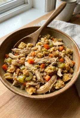A close-up of shredded chicken mixed with savory stuffing and chunks of carrots and celery.