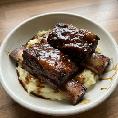 A close-up of a fork cutting into a tender piece of a slow-cooked short rib.
