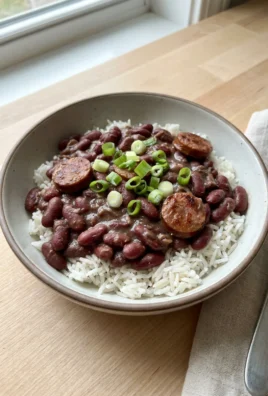 A spoonful of red beans and rice showing the creamy texture and chunks of sausage.