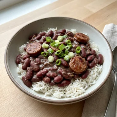 A spoonful of red beans and rice showing the creamy texture and chunks of sausage.