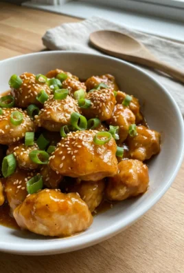 Slow cooker orange chicken served over white rice in a rustic ceramic bowl.