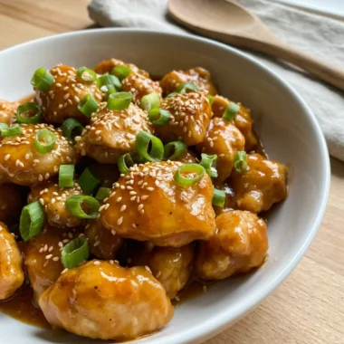 Slow cooker orange chicken served over white rice in a rustic ceramic bowl.